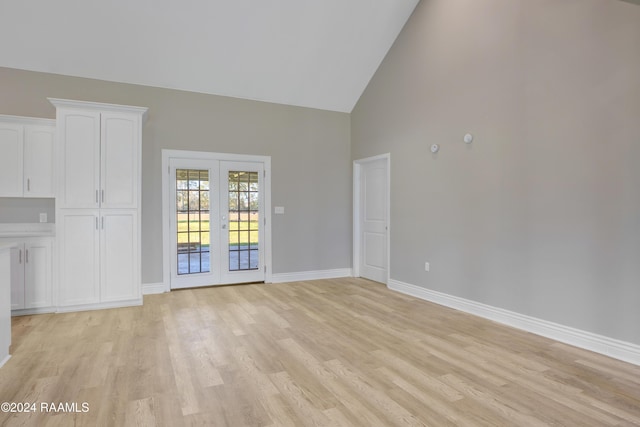 unfurnished living room with french doors, high vaulted ceiling, and light hardwood / wood-style flooring