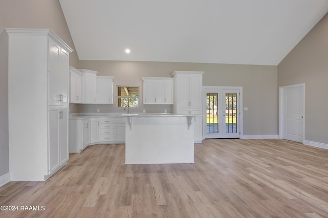 kitchen with a center island, white cabinets, plenty of natural light, and high vaulted ceiling