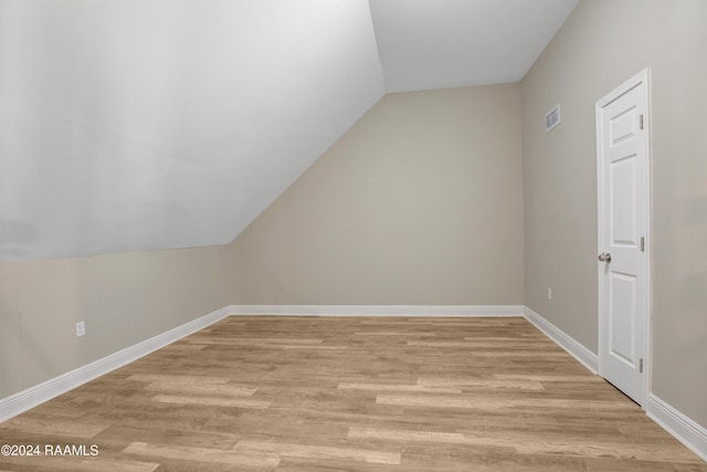 additional living space featuring vaulted ceiling and light wood-type flooring