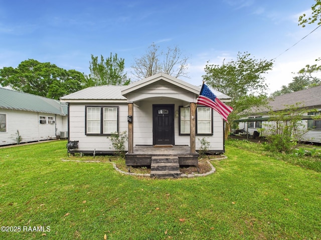 bungalow-style home featuring a front lawn, metal roof, and central AC unit