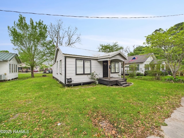 view of front of home with central air condition unit, metal roof, and a front yard