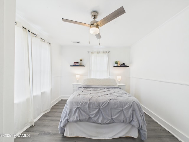 bedroom with baseboards, visible vents, a ceiling fan, and wood finished floors