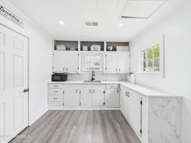 kitchen with a sink, open shelves, black microwave, visible vents, and a healthy amount of sunlight