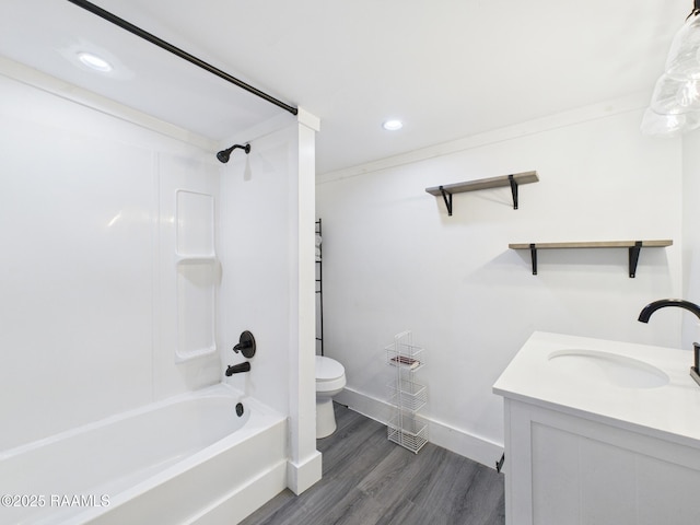 bathroom with baseboards, toilet, wood finished floors, vanity, and shower / bath combination