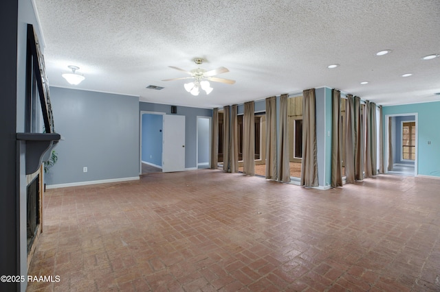 unfurnished living room featuring ceiling fan, a textured ceiling, and a fireplace