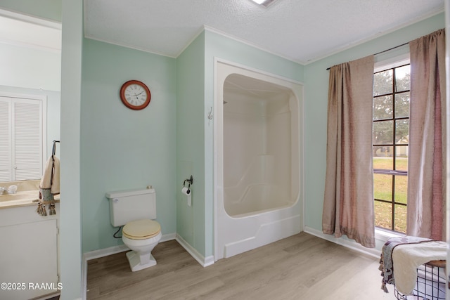 bathroom with hardwood / wood-style floors, a textured ceiling, vanity, a shower, and toilet