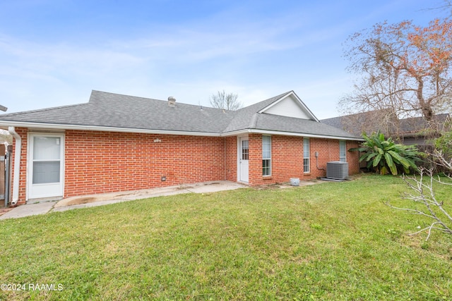 rear view of property featuring a lawn and central AC unit