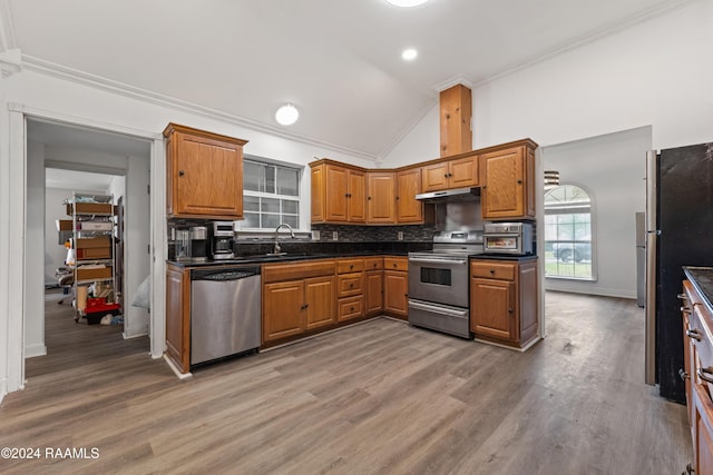 kitchen with sink, stainless steel appliances, backsplash, hardwood / wood-style floors, and lofted ceiling