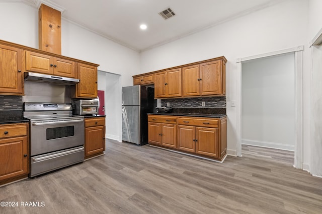 kitchen featuring light hardwood / wood-style floors, ornamental molding, appliances with stainless steel finishes, and tasteful backsplash