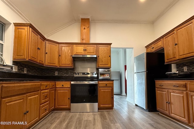 kitchen with lofted ceiling, crown molding, appliances with stainless steel finishes, hardwood / wood-style floors, and decorative backsplash