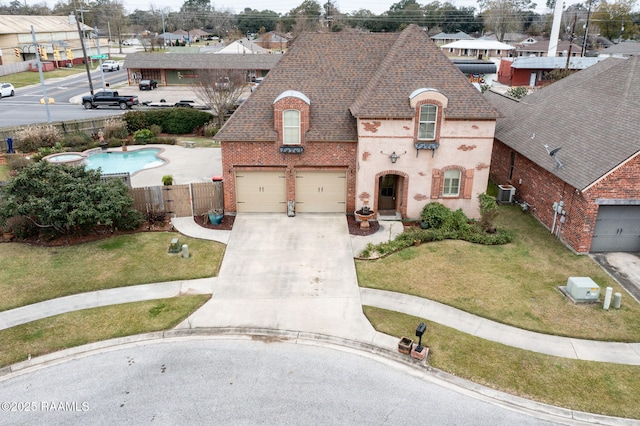 french country home featuring a front lawn, fence, roof with shingles, concrete driveway, and brick siding