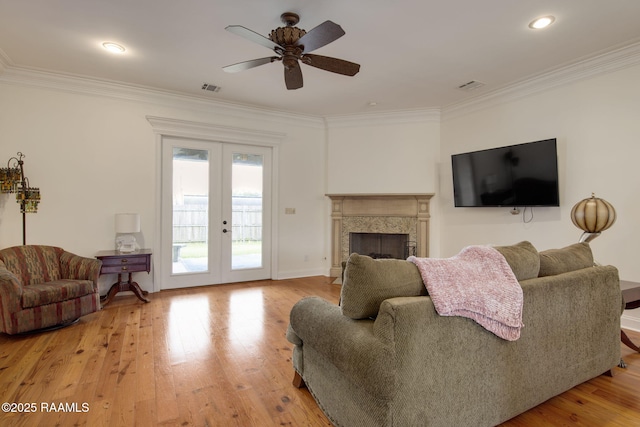 living area with french doors, visible vents, light wood finished floors, and ornamental molding