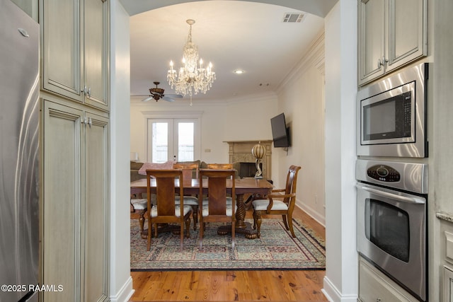 dining space with visible vents, baseboards, light wood-style floors, crown molding, and a notable chandelier