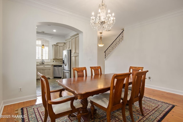 dining space featuring sink, ornamental molding, light hardwood / wood-style flooring, and a chandelier