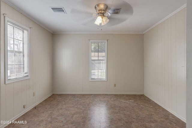 spare room featuring wood walls, plenty of natural light, ornamental molding, and ceiling fan