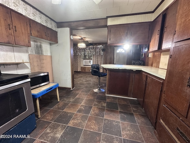 kitchen featuring kitchen peninsula, appliances with stainless steel finishes, ornamental molding, and a kitchen breakfast bar