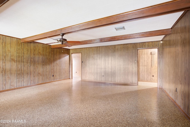 empty room featuring wooden walls, beamed ceiling, and ceiling fan