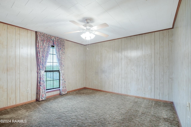 spare room featuring ceiling fan, carpet floors, and wooden walls