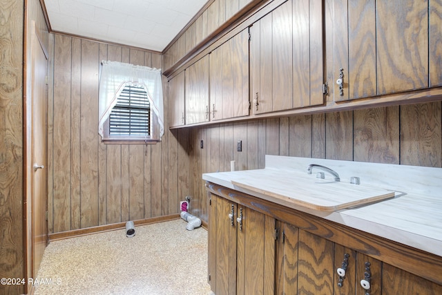 clothes washing area with cabinets and wooden walls