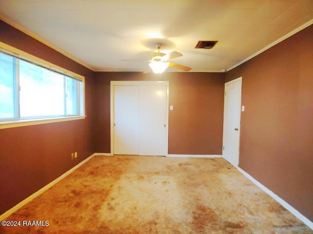 unfurnished bedroom featuring carpet, a closet, crown molding, and baseboards