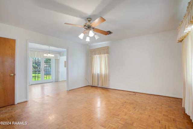 empty room with light parquet floors and ceiling fan with notable chandelier