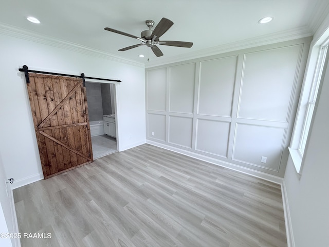 213 Berchman Oaks Dr, Lafayette, LA 70506 - unfurnished bedroom with light wood-style flooring, a barn door, baseboards, crown molding, and a decorative wall