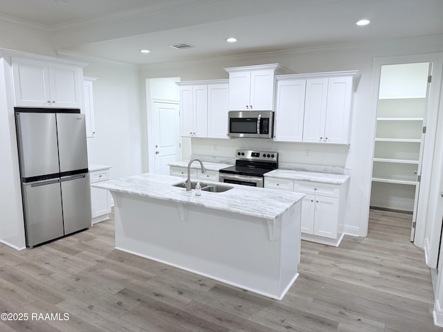 kitchen with white cabinets, sink, stainless steel appliances, and a center island with sink