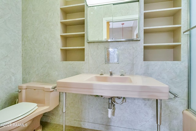 bathroom featuring built in shelves, toilet, and enclosed tub / shower combo