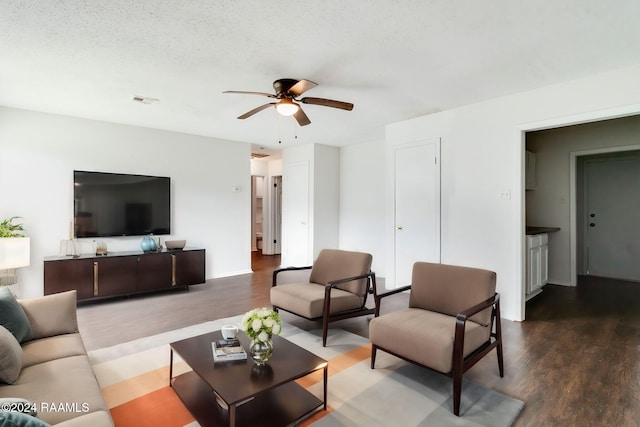 living room featuring wood-type flooring, a textured ceiling, and ceiling fan