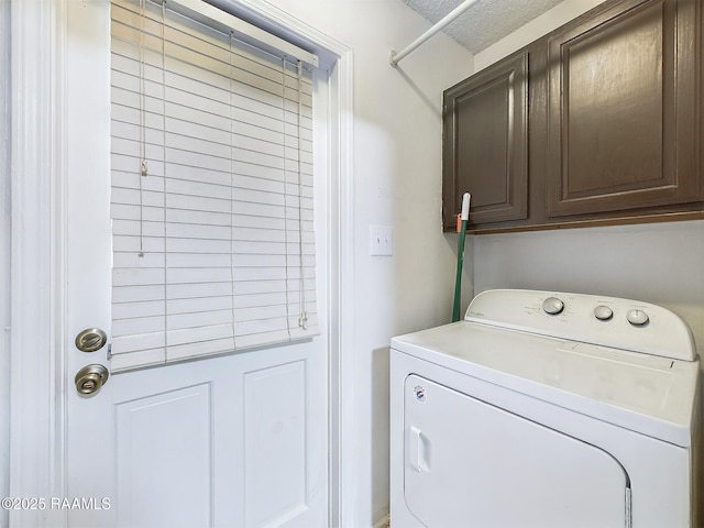 clothes washing area featuring washer / dryer, cabinets, and a textured ceiling