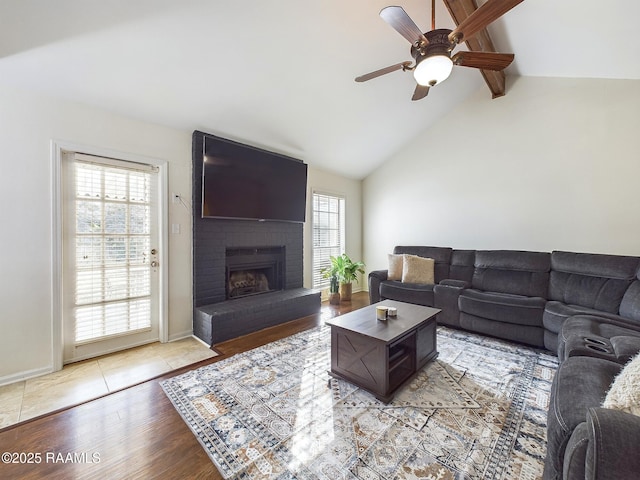 living room featuring vaulted ceiling with beams, light hardwood / wood-style floors, plenty of natural light, and a brick fireplace