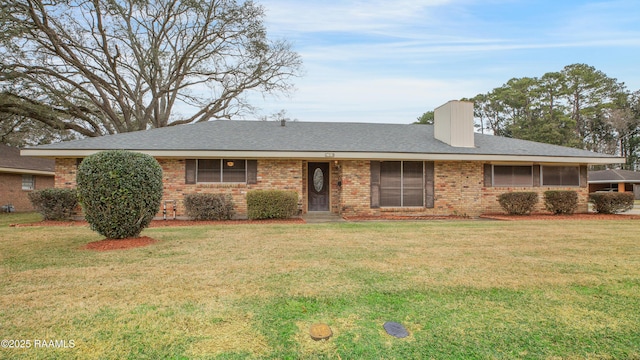 ranch-style house with brick siding, a chimney, a front lawn, and roof with shingles