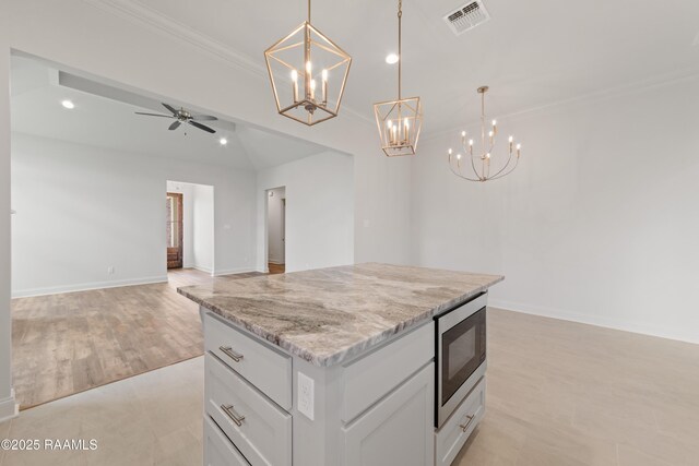 102 Fillmore Way, Lafayette, LA 70506 - kitchen with stainless steel microwave, a chandelier, a kitchen island, open floor plan, and crown molding