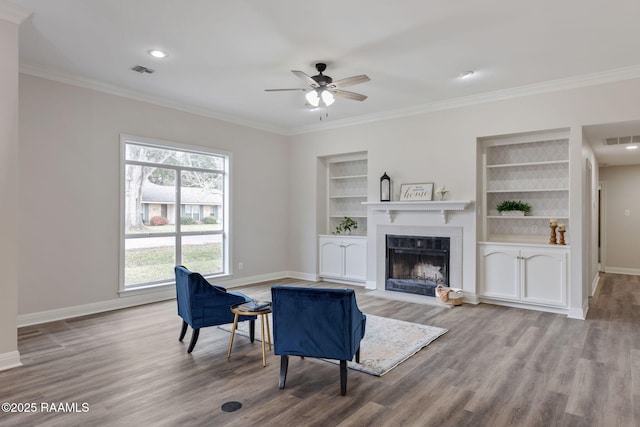 living room featuring built in shelves, ceiling fan, plenty of natural light, and hardwood / wood-style flooring