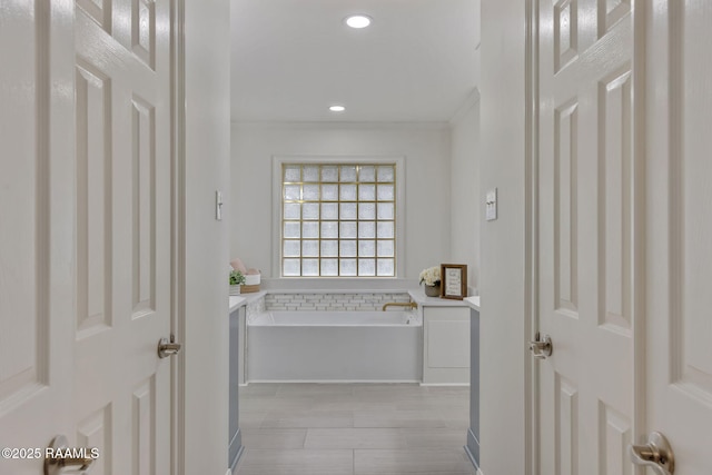 bathroom with a washtub, wood-type flooring, and ornamental molding