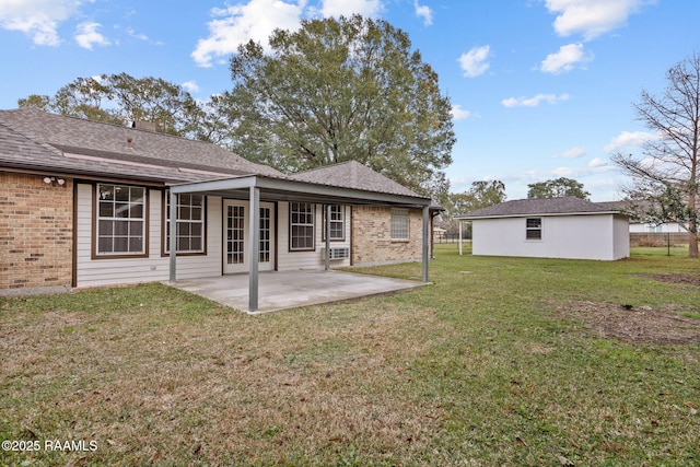 rear view of house with an outdoor structure, a patio area, and a lawn