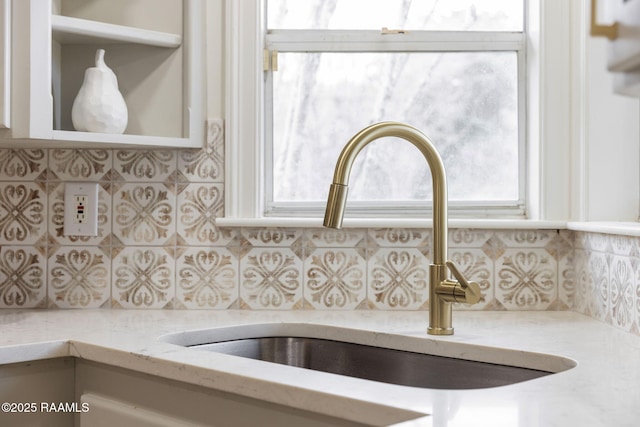 details featuring light stone countertops, tasteful backsplash, and sink