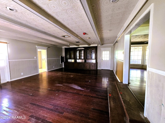 unfurnished living room with dark hardwood / wood-style floors and beam ceiling