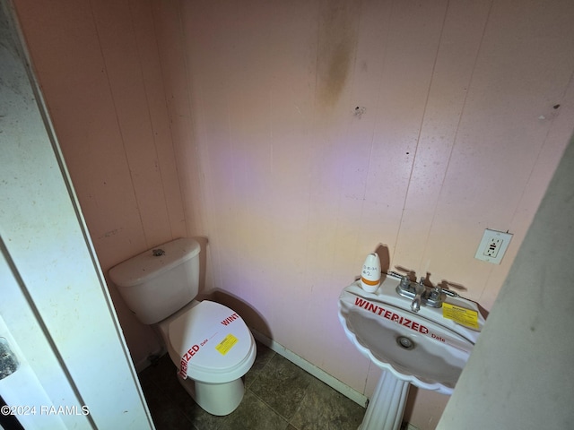 bathroom featuring wooden walls, sink, and toilet