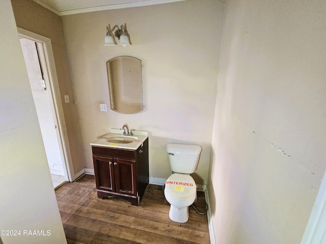 bathroom featuring wood-type flooring, vanity, toilet, and crown molding