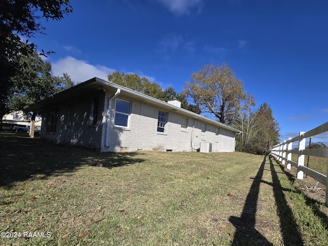 view of side of home featuring a lawn and central air condition unit