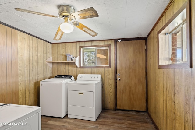 clothes washing area featuring hardwood / wood-style floors, washer and clothes dryer, and wood walls