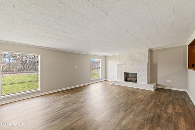 unfurnished living room featuring plenty of natural light, dark hardwood / wood-style floors, and a brick fireplace