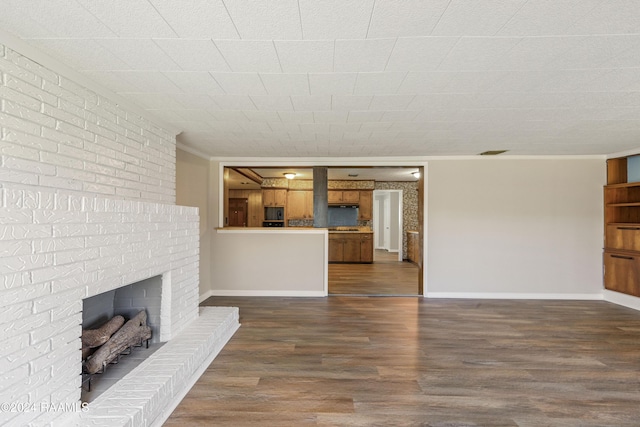 unfurnished living room featuring dark wood-type flooring, crown molding, and a brick fireplace