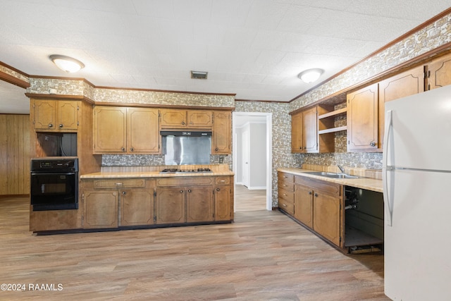 kitchen with stainless steel gas cooktop, white fridge, light hardwood / wood-style floors, oven, and ornamental molding