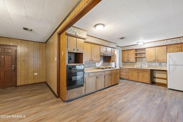 kitchen featuring stainless steel gas stovetop, oven, white refrigerator, sink, and light wood-type flooring