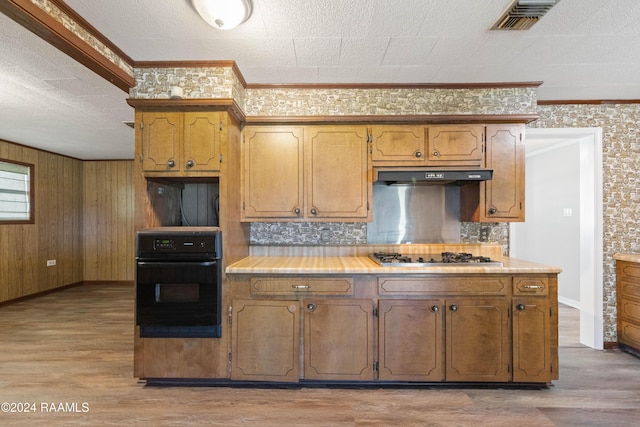 kitchen with light hardwood / wood-style flooring, backsplash, oven, stainless steel gas stovetop, and ornamental molding