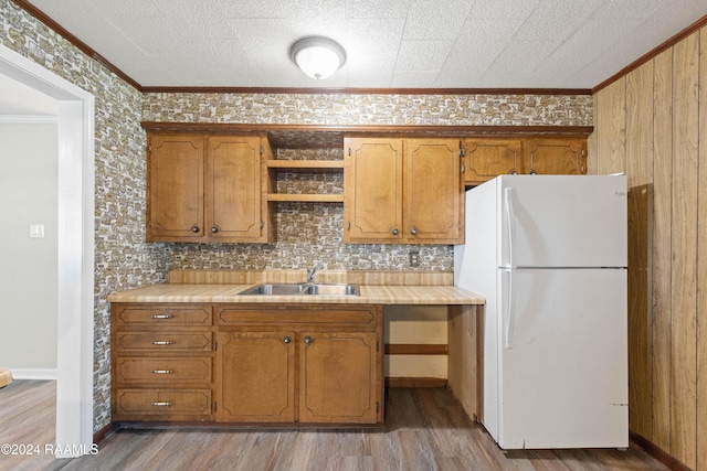 kitchen featuring white refrigerator, sink, light hardwood / wood-style flooring, decorative backsplash, and ornamental molding