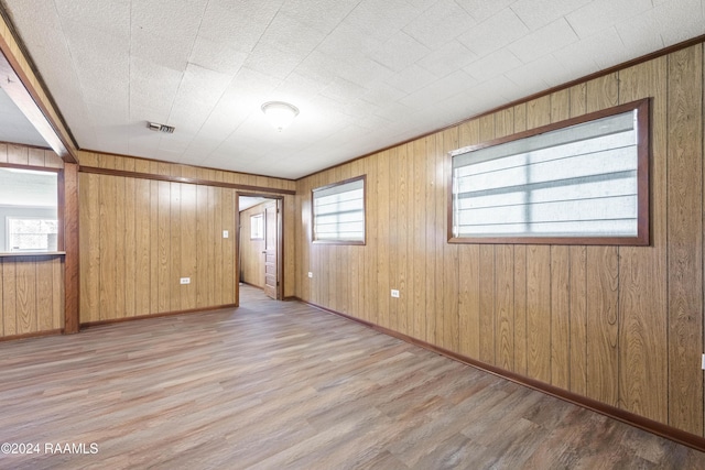 spare room with wood walls and light hardwood / wood-style flooring