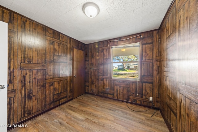 empty room with wooden walls and light hardwood / wood-style flooring